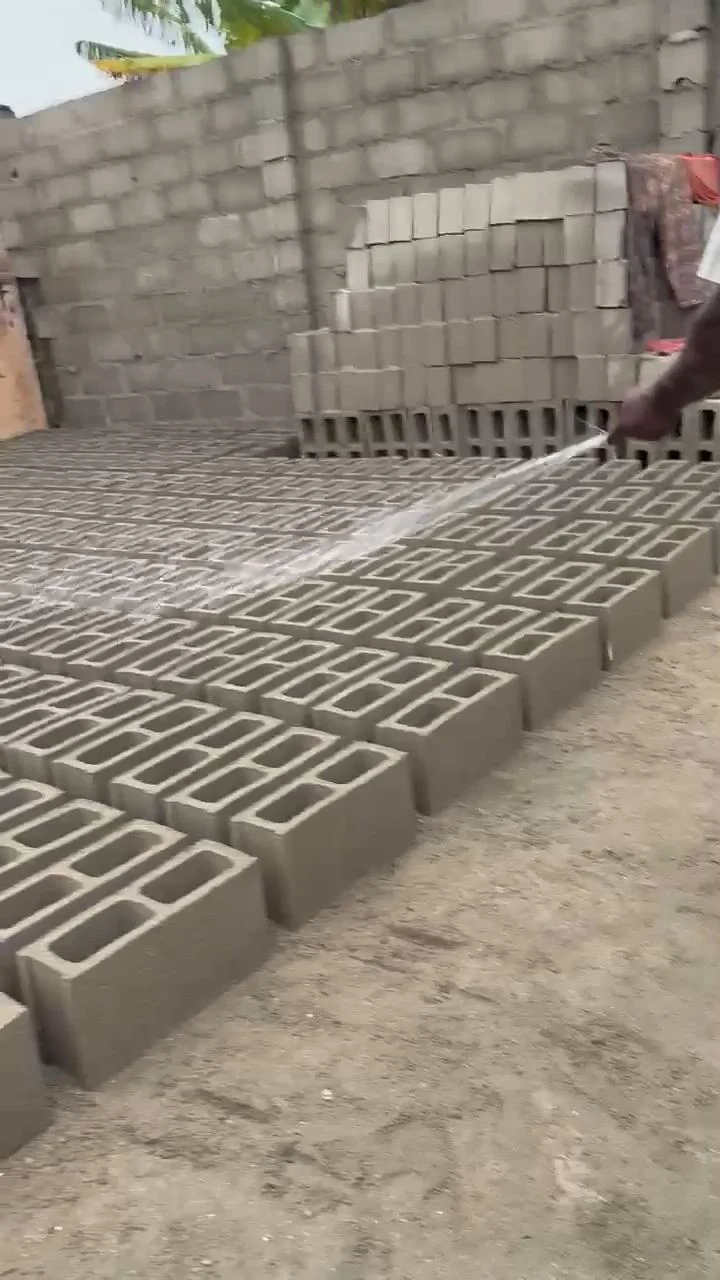 A worker watering freshly moulded blocks so they cure to full strength